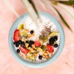Os Incríveis Benefícios da Chia para a Sua Saúde: Guia Completo Sementes de chia em uma tigela de madeira com fundo desfocado de frutas e iogurte