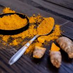 Açafrão: 7 Benefícios Comprovados para a Sua Saúde e Como Usar Fios de açafrão vermelho vibrante em uma colher de madeira, simbolizando saúde e bem-estar.